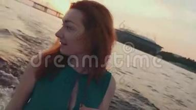 穿着绿松石衣服的年轻女孩在摩托艇上摸头发。 看日落。 浪漫浪漫